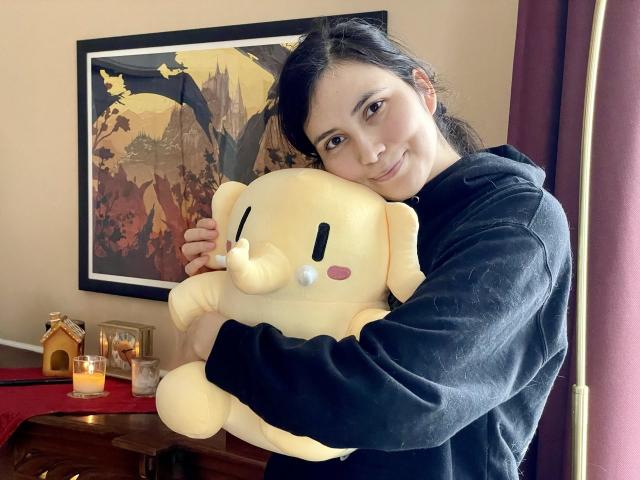 まるいMastodonのぬいぐるみ。ベージュ色で頬をピンク色に染めている。私の妻に抱きかかえられて大きく見える。