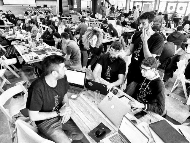 jóvenes hackers reunidos en decenas de mesas construyendo en común