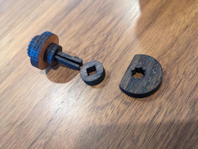 A close-up of the locking pins, showing how they can be removed and reconfigured to encode any combination. They consist of a central pin with five discs:
The first is a grip.
The second is the number plate, which is bigger than the hole in the door.
The third fits snugly inside the hole in the door, and acts as the hinge
The fourth is slightly larger than the hole in the door, and acts as a spacer.
The fifth is late with a cord cut off. This engages with the locking bar unless the cut cord is flush with the bar.