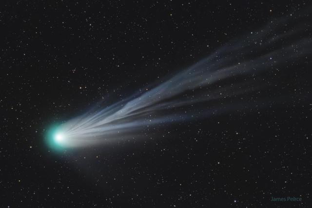 A large comet is shown with its head near the right and a light blue flowing ion tail flowing across into the rest of the image.