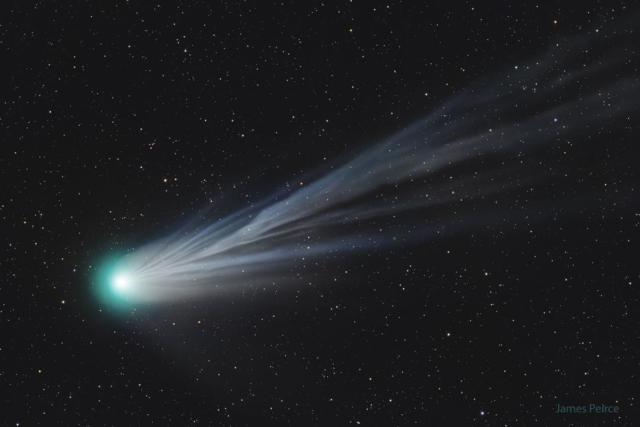 A large comet is shown with its head near the right and a light blue flowing ion tail flowing across into the rest of the image.