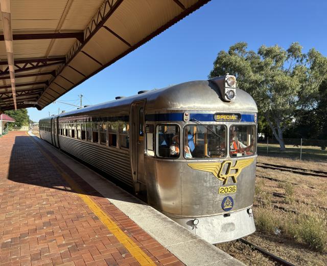 Streamlined steel-body train, with a curved nose bearing a chunky yellow "QR" logo with wings.