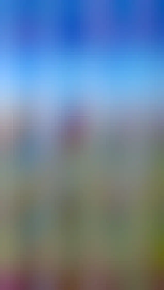 A man and child walking along the beach with wave washing against them