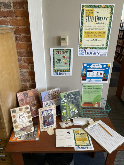 Books on seed libraries, harvesting seeds, and various fliers announcing the seed library. 