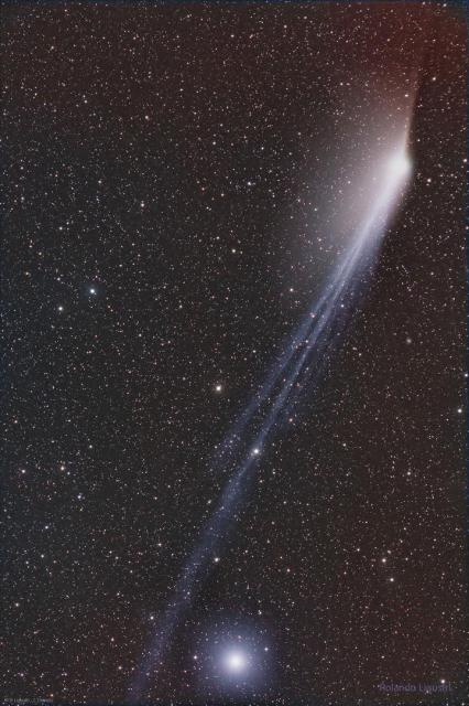 A dark star filled sky is shown with the wisps extending the length of the image. The wisps are the two tails of Comet 12P. A particularly bright star is visible near the bottom of the frame.