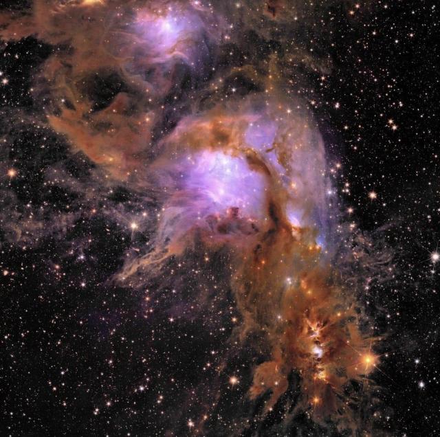 Deep orange clouds of gas and dust swirl diagonally across the image. At center, bright stars give the region a purple hue. In the background is the black backdrop of space, dotted with bright stars and galaxies. Credit: ESA/Euclid/Euclid Consortium/NASA, image processing by J.-C. Cuillandre (CEA Paris- Saclay), G. Anselmi; CC BY-SA 3.0 IGO or ESA Standard License