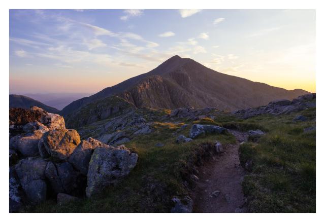A path leading to a mountain summit during sunrise
