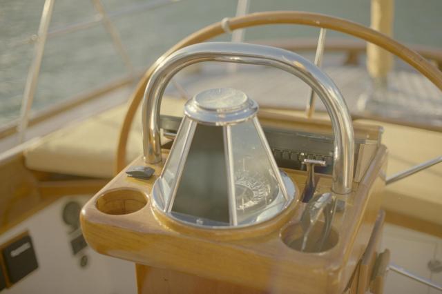 A compass shaped like a pyramid next to the steering wheel of a boat.