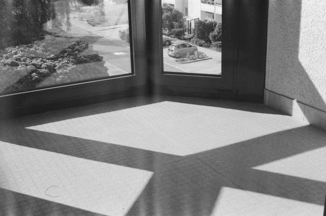 A black and white photo of a large window casting a geometric shadow onto the floor.