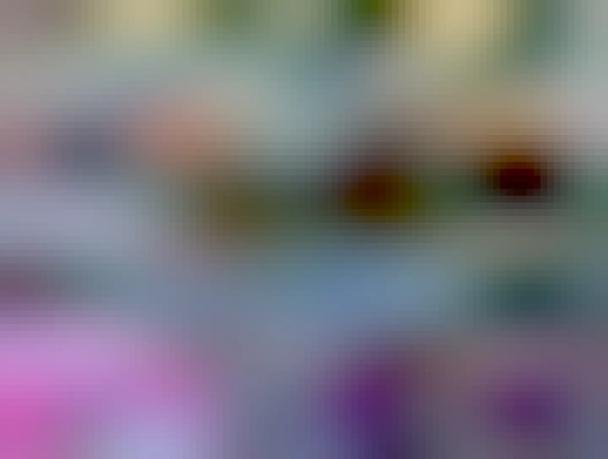 An orange cat on a gray couch stretching out facing away from the camera.The cat's front legs are down on the seat of the couch, and his back legs are up on the backrest of the couch, and he looks really long.