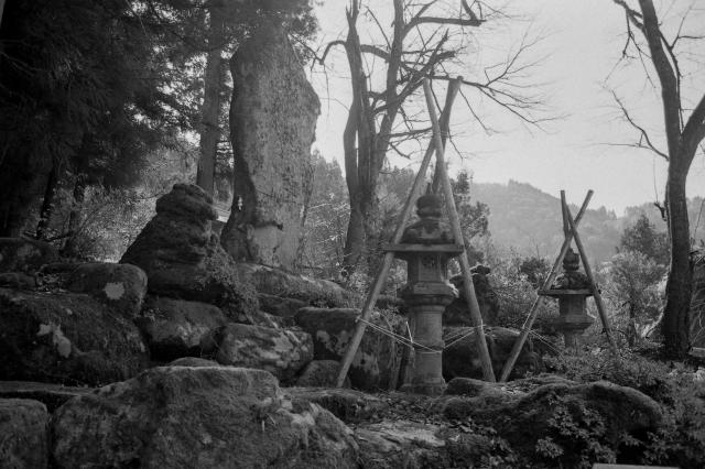 Black and white film photo of stone lanterns and rocks in Shirakawago village. 