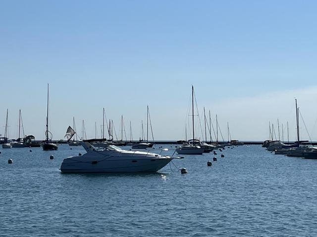 A photo of Lake Michigan. The waters are calm and there are many boats anchored at the marina.