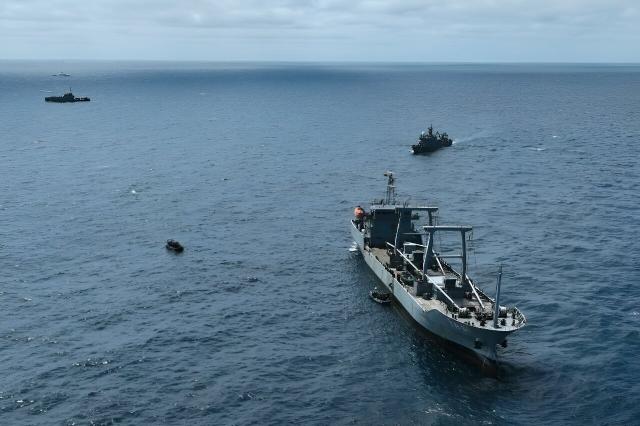 a large fishing vessel being intercepted by a small fotilla of military vessels 