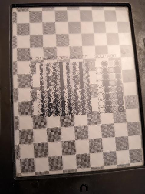 An e-ink screen showing a checkerboard pattern with a grid of pixelated shapes showing off the various blend modes of the Varvara screen device.