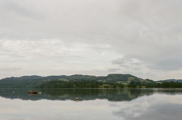 A large body of water with a red boat in it. Behind, a landscape.