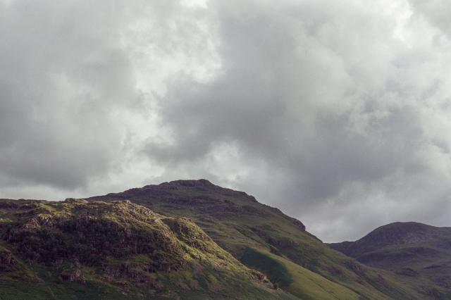 Fells partially illuminated by the evening sun, partially in shadow from the heavy clouds above.