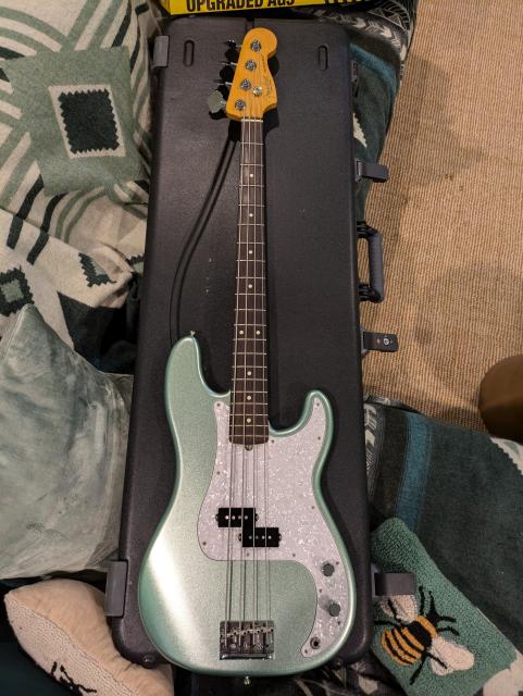 A Fender Precision Bass in mystic surf green finish with a rosewood fretboard