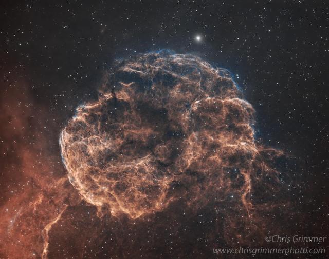 Bright Nebula, appearing like a jellyfish in bright orange reds representing Hydrogen gas, and fainter blues around the edge from oxygen. Also looks a little like a brain.