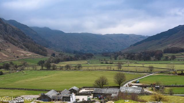 A Valley surrounded by hills with a farm in the foreground and fields 