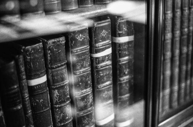 Very old books on a bookshelf behind glass.