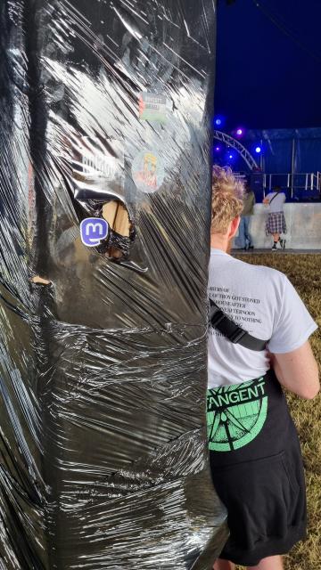 A pillar in  a tent at ArcTanGent Festival, with a Mastodon sticker on it 