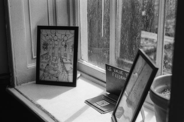 A windowsill with two framed artworks facing inwards. The dust on the window reflects sunlight in an appealing way.