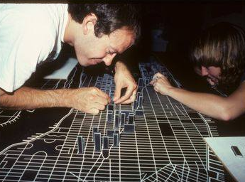 special effects technicians apply reflective tape to a miniature city