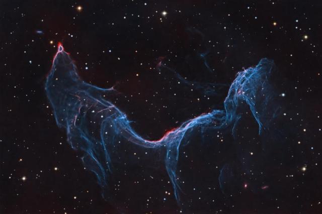 A starfield is shown with a long blue-glowing nebula taking up much of the frame. The nebula appears, to some, similar to a fish or a mermaid.