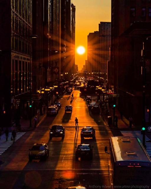 A picture of the Sun setting at the end of a long city street is shown.