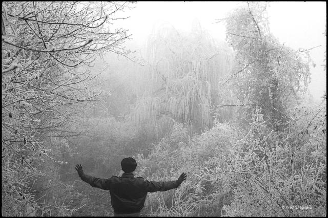 In a path completely white with frost, someone stretches her arms as if to push aside the ice. Horizontal photo taken on 35mm black and white film. 