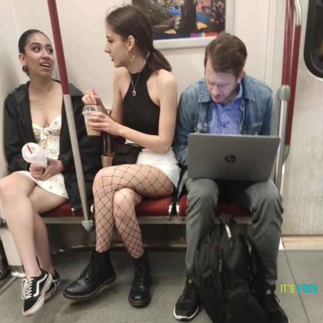 There are two women sat beside a man, who is busy looking at his laptop.