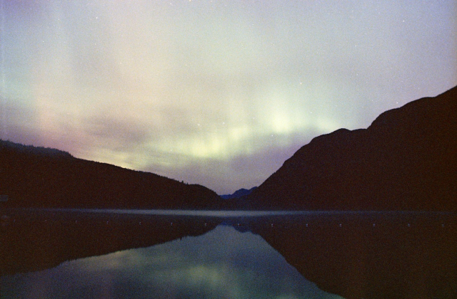 multicolor aurora over a lake with distant mountains