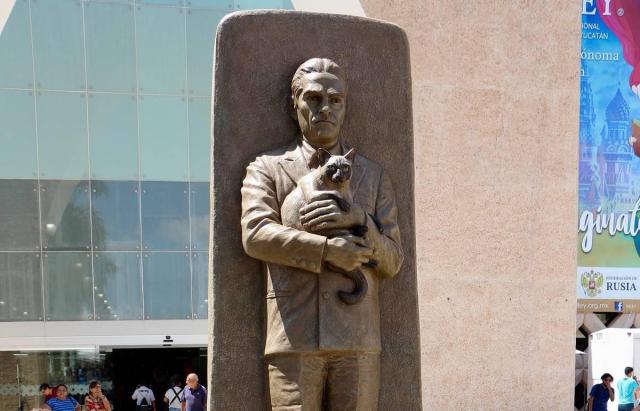 Image of the monument. Looks like the guy, holding the cat cradled in his arms, is walking through a doorway