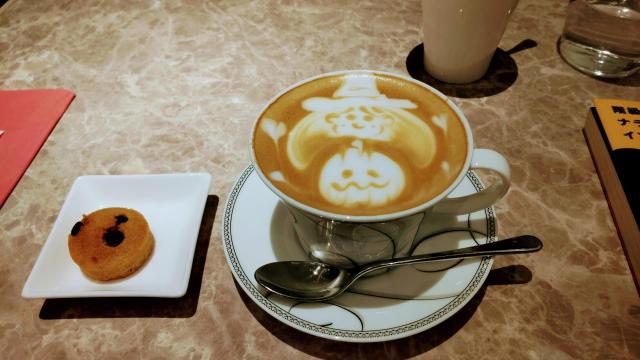 魔女とかぼちゃのラテアートが施されたカフェラテとフィナンシェ