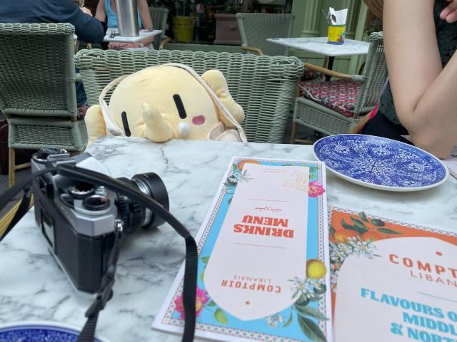 A stuffed Mastodon toy sitting in front of a restaurant table.