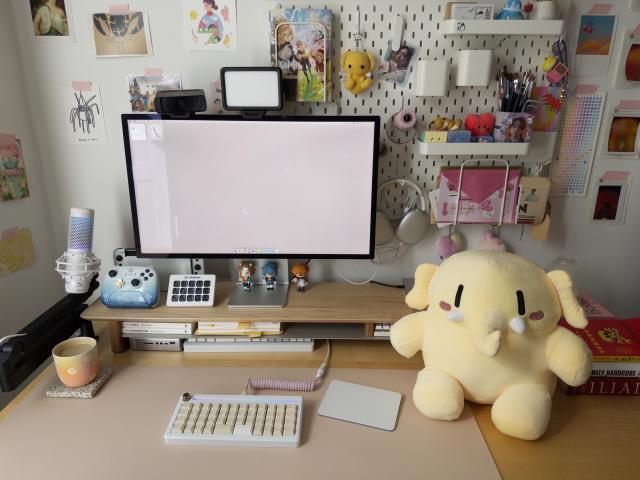 a photo of my desk, with the big yellow mastodon plushie sitting on top of it, next to my keyboard & trackpad