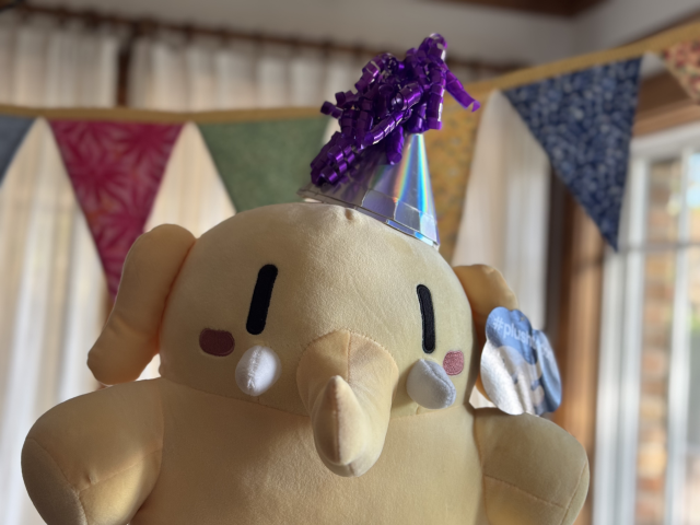 Plushtodon wearing party hat