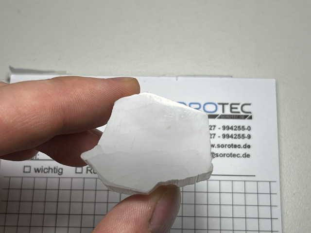 Same piece viewed from above being held from a distance above a piece of printed paper