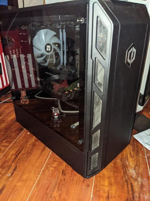 Photo of a desktop PC in a bedroom. PC is black with a glass panel to reveal the components inside