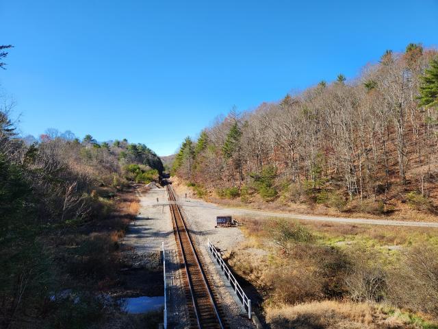 View of train tracks heading off into the distance. Hills with trees on both sides.