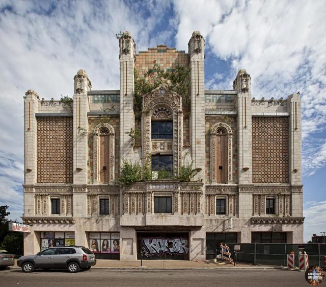 A spectacular theater facade covered with beautiful tile and stone work. Plants are sprouting from various ledges, and the front entrance is boarded and covered with graffiti