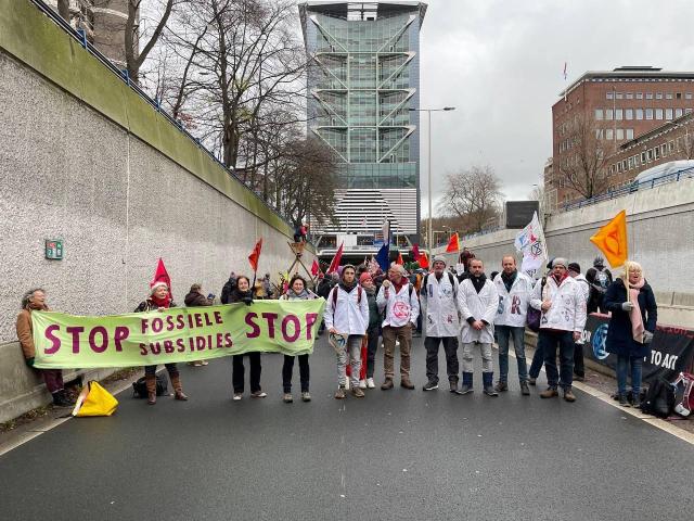 A few dozen demonstrators are standing on the A12 highway in The Hague. They are waving flags, and a banner saying 'Stop fossiele subsidies'.