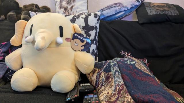 A mastodon plush lurking on my messy/comforting sofa. They have the various telly remotes to hand, an old LL Bean throw, and a Test Dept cushion for when it gets cold. Vice Grip Garage is streaming, and the tea is still warm.