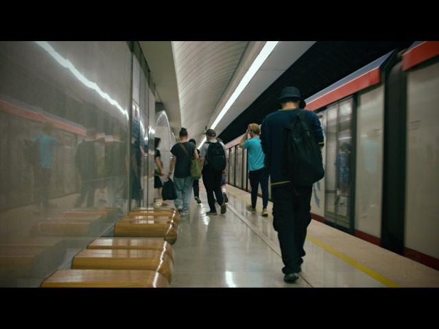 A photo of an underground train station with a train ready to departure and people going from it toward main gallery