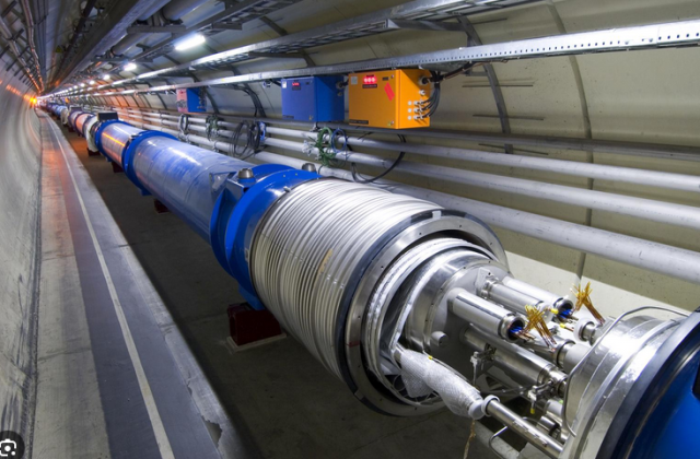 screenshot of image of CERN particle accelerator showing a huge tube in a tunnel and interior components.