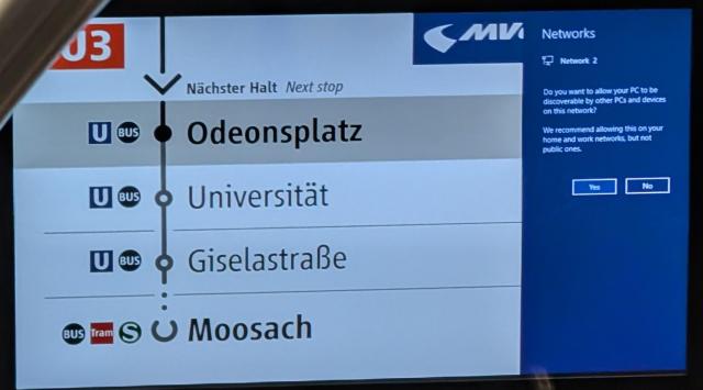 Munich subway display showing the next stops, but with a Windows "Networks" prompt open, asking if the PC should be discoverable by other devices on the network.