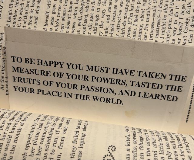 A bookmark laying in a book. It reads: TO BE HAPPY YOU MUST HAVE TAKEN THE MEASURE OF YOUR POWERS, TASTED THE
FRUITS OF YOUR PASSION, AND LEARNED YOUR PLACE IN THE WORLD.