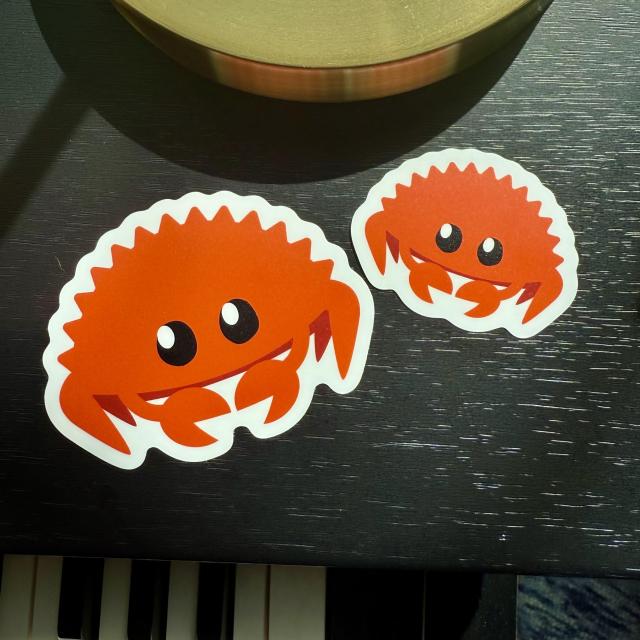 Two cute orange crab stickers of different sizes sitting on a piano
