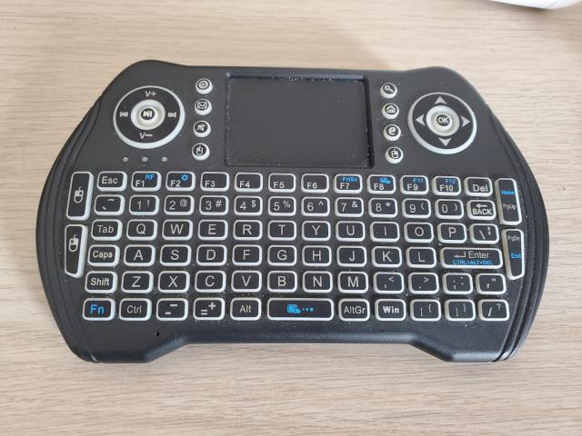 A plastic doohickey that's flat but shaped kind of like a game controller. The bottom has a keyboard with the type of mushy rubber buttons you'd expect on a cheap TV remote. In the top is a touch pad flanked by media buttons on the left and arrow buttons on the right. There are also dedicated mouse left and right buttons next to the keyboard