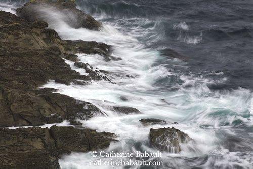 Long exposure of waves crashing on a rocky shoreline.